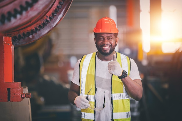 Portrait african american black afro worker in factory cameroon\
black man employee work in production plant manufacture factory\
industry and operator line machine steel metal using helmet for\
safety