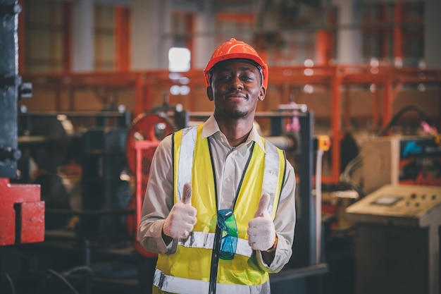 Ritratto afroamericano nero afro lavoratore in fabbrica camerun uomo nero dipendente lavoro in stabilimento di produzione fabbrica industria e linea operatore macchina acciaio metallo utilizzando casco per la sicurezza