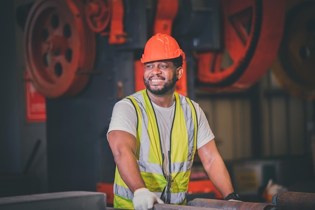 Ritratto afroamericano nero afro lavoratore in fabbrica camerun uomo nero dipendente lavoro in stabilimento di produzione fabbrica industria e linea operatore macchina acciaio metallo utilizzando casco per la sicurezza