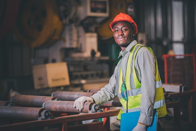 Portrait african american black afro worker in factory cameroon\
black man employee work in production plant manufacture factory\
industry and operator line machine steel metal using helmet for\
safety