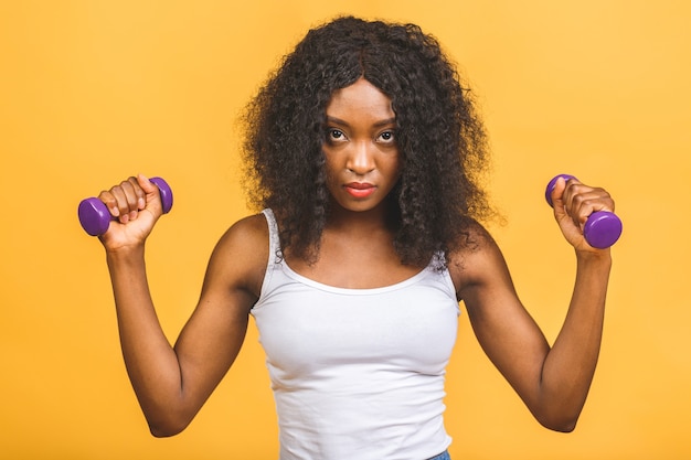 Portrait of african american black young woman exercising her muscle with dumbbells