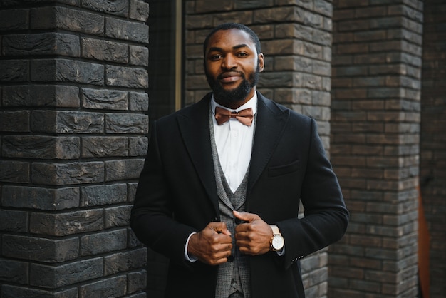 屋外のビジネス環境で立っているスーツを着ているアフリカ系アメリカ人のビジネスマンの肖像画