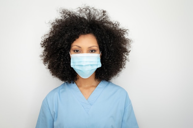 Photo portrait of african american female healthcare worker with afro hair wearing face mask, looking at camera. medical profession, hygiene during coronavirus covid19 pandemic.