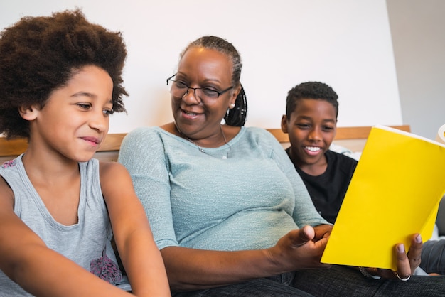 Portrait of African American grandmother reading a book to her grandchildren at home. Family concept.