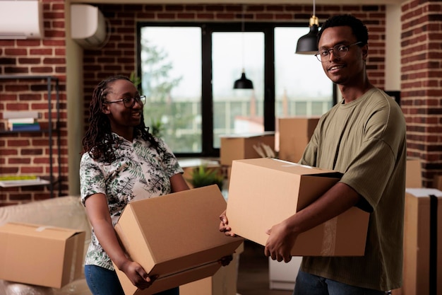 Portrait of african american homeowners feeling happy about moving household, starting new beginning for future family. Enjoying home relocation with furniture, romantic life event.