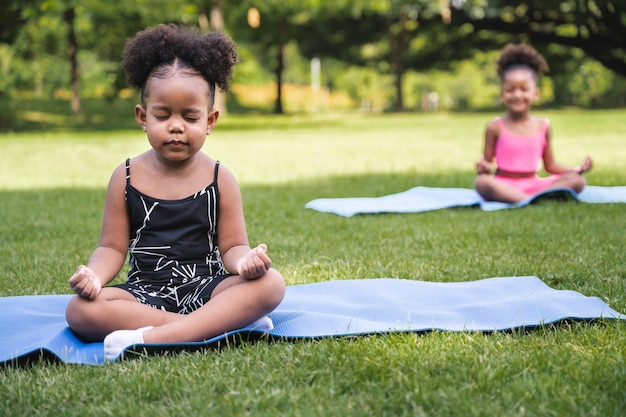 Portrait African American kid girl training yoga meditate in the park