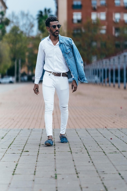 Ritratto di un uomo afroamericano vestito di bianco che cammina per strada