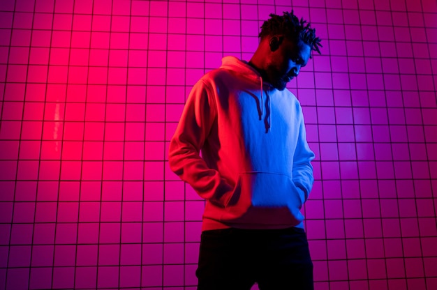 Portrait of an African American man in a hoodie on a neon background. Red-blue background. 