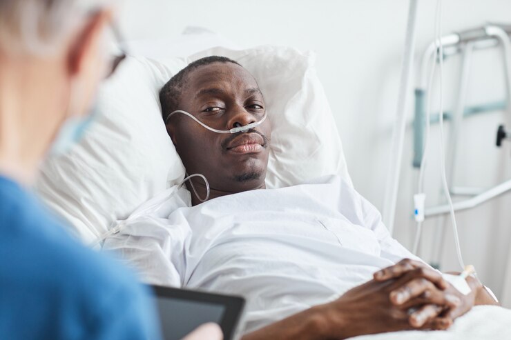 Photo portrait of african-american man lying in hospital bed and looking at doctor, copy space