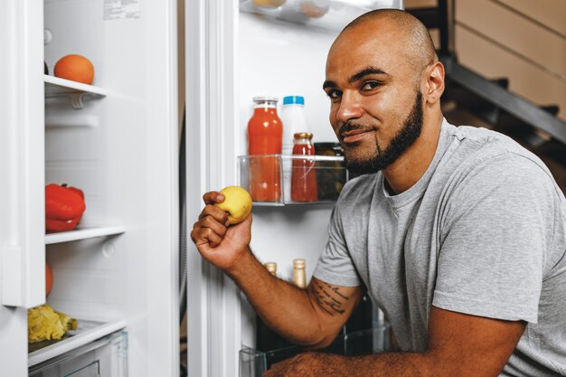 Portrait of African american man taking food from a fridge in his house