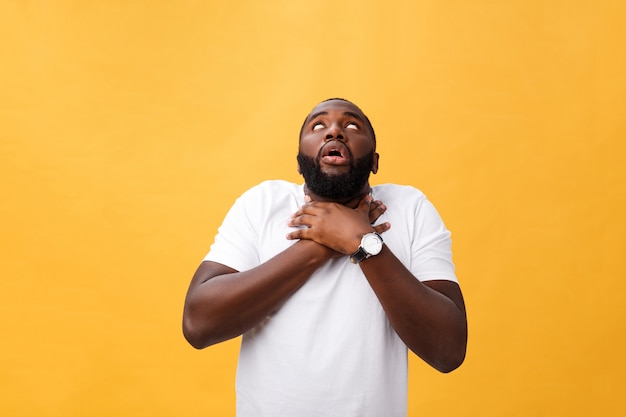 Portrait of african american man with hands raised in shock and disbelief. Isolated over yellow background.