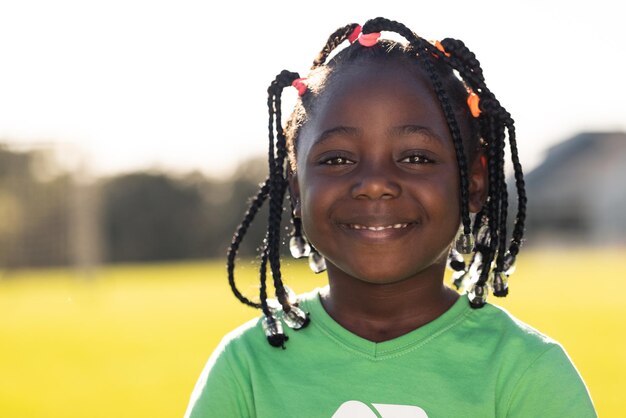Portrait of african american schoolgirl smiling in sunny elementary school sports field copy space