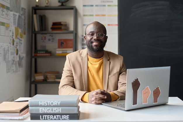 Portrait of african american teacher smiling at camera while sitting at table