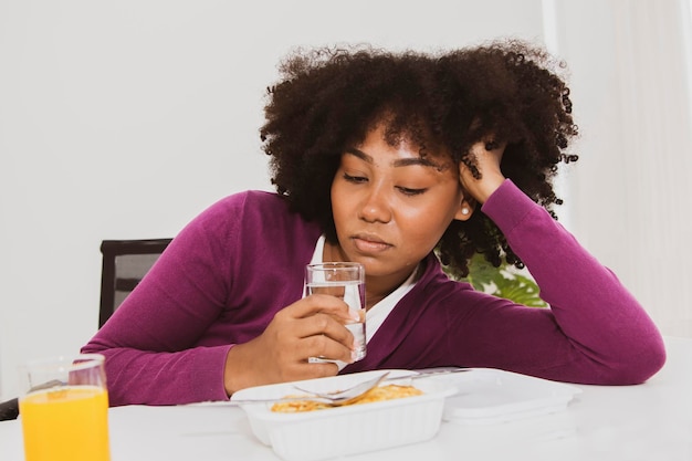 Portrait african american teenager holding glass of water looking poorly nutritious lunchbox