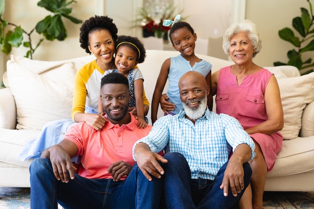 Foto ritratto di una famiglia afroamericana di tre generazioni che sorride mentre si siedono insieme sul divano di casa. concetto di famiglia, amore e unione, inalterato.