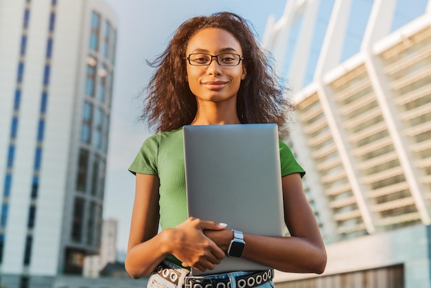 Ritratto di donna afroamericana che tiene il computer portatile all'aperto