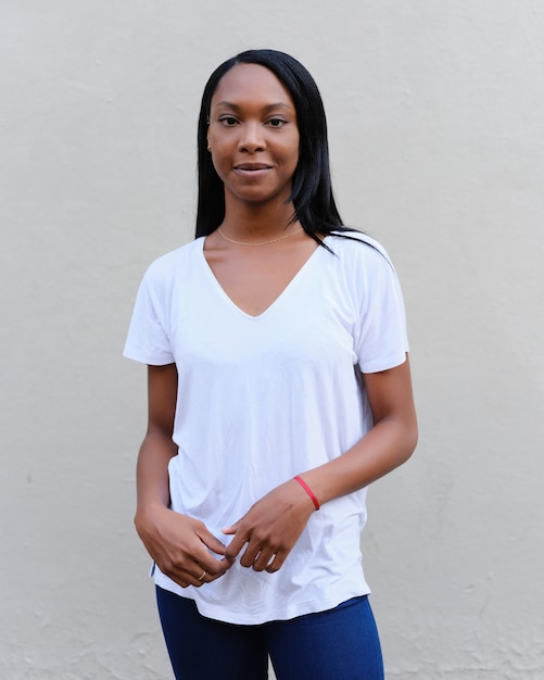 Portrait of an african american woman looking to the camera while standing against a wall outdoors.