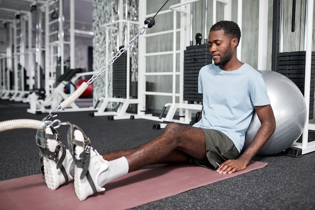 Portrait of african american young man doing rehabilitation\
exercises in gym at physiotherapy clinic