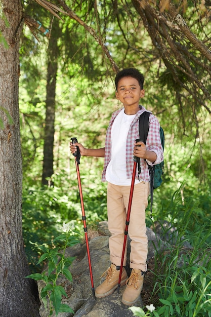 棒で立っているアフリカの少年の肖像画と彼の旅行中に森