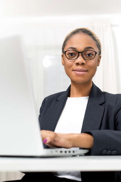 Portrait of African business smiling woman working at laptop.