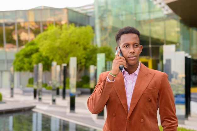 Портрет африканского бизнесмена на открытом воздухе с помощью мобильного телефона