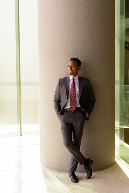 Portrait of African businessman wearing suit and tie outdoors in city while thinking