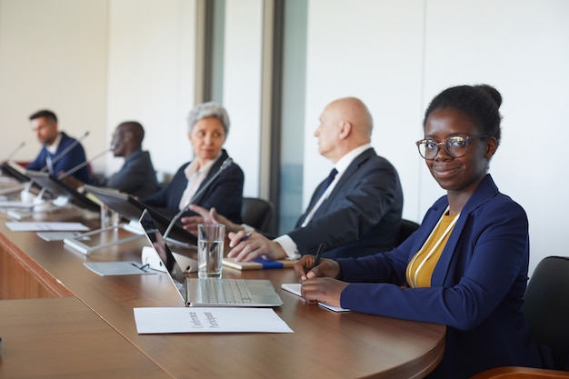 Портрет африканской бизнес-леди, глядя, сидя со своими коллегами на бизнес-конференции