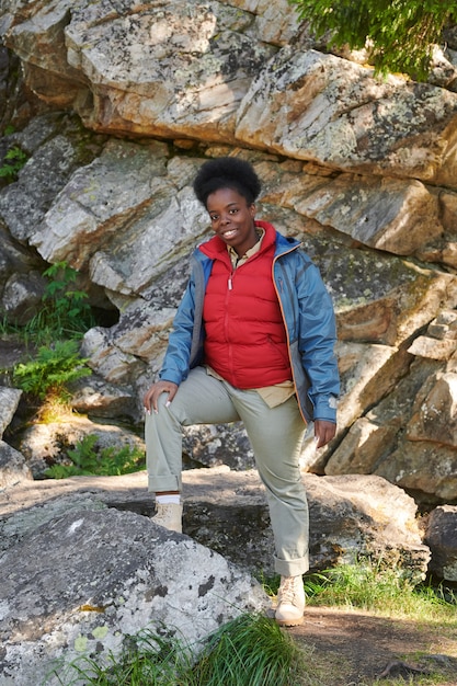 Portrait of African female tourist in warm clothing smiling at camera during her trip in the nature