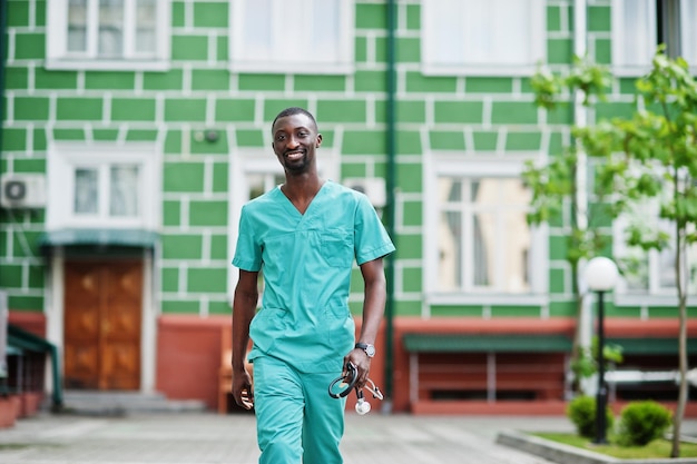 Portrait of African male doctor with stethoscope wearing green coat.