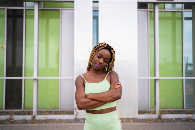 Portrait of an african sportive woman posing with arms crossed in front of a modern facade