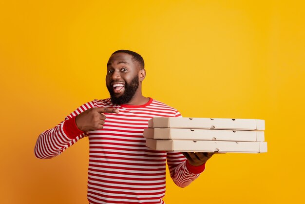 Portrait of african student courier hold stack pizza boxes point finger promoting advertisement