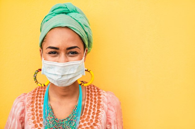 Portrait of african young woman wearing face protective mask - Happy woman wearing bohemian clothes during coronavirus outbreak - Ethnic and Covid19 lifestyle