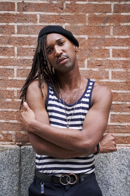 Portrait of an AfricanAmerican man with dreadlocks posing on a brick wall