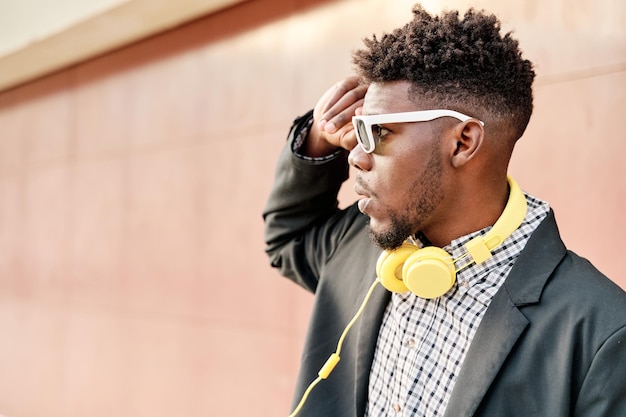 Ritratto di un uomo afroamericano con occhiali da sole che si toccano i capelli