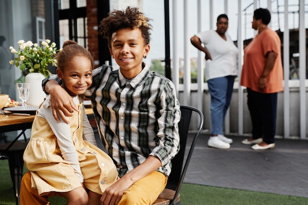 Portrait of africanamerican teenage boy posing with little sister during family gathering outdoors c...