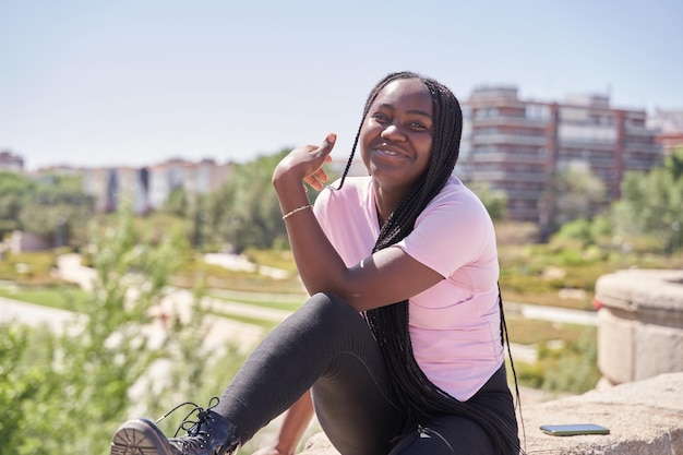 Portrait of an AfricanAmerican woman with braids posing with the city in the background