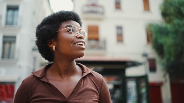 Portrait of Afro American dark haired girl looking cheerful walk around city Happy expression