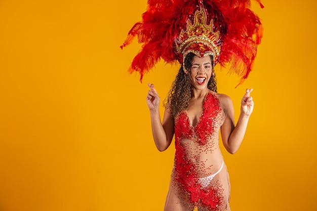 Portrait of afro brazilian woman in carnival outfit with fingers crossed wishing luck. Carnival dancer woman crosses her fingers waiting for the result of the placement of the samba school