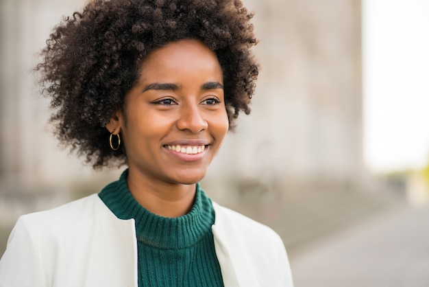 Portrait of afro business woman smiling while standing outdoors on the street