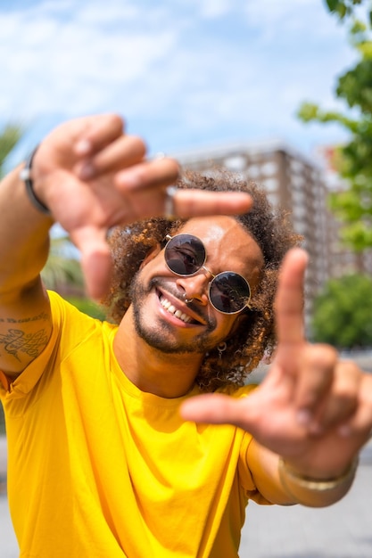 Portrait of an afrohaired man in a yellow tshirt portrait in the city smiling on summer vacation