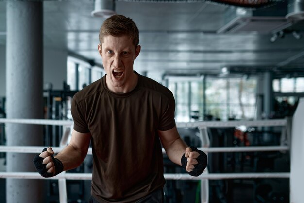 Portrait of aggressive boxer holding clenched fists ready to\
boxing in sport ring