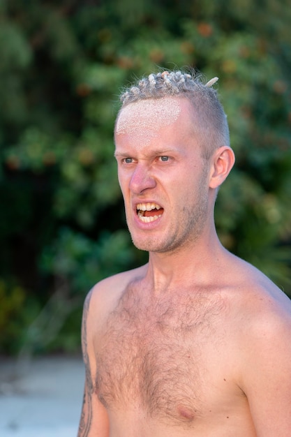 Портрет агрессивного молодого человека с дредами на голове на природе на тропическом пляже, крупным планом