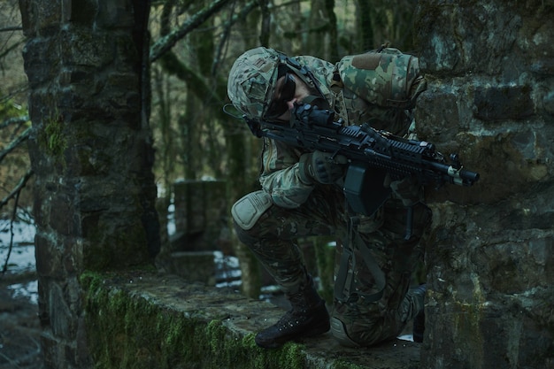 숲에서 총으로 피해자를 목표로 헬멧에 전문 장비에서 airsoft 선수의 초상화. 전쟁에서 무기를 든 군인
