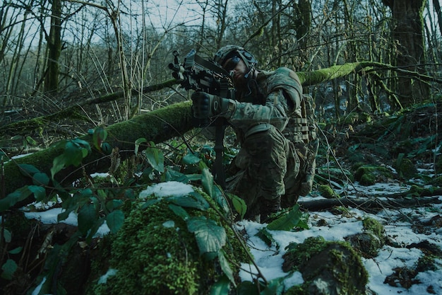 Портрет страйкбола в профессиональном оборудовании в шлеме, нацеленного на жертву с ружьем в лесу. Солдат с оружием на войне