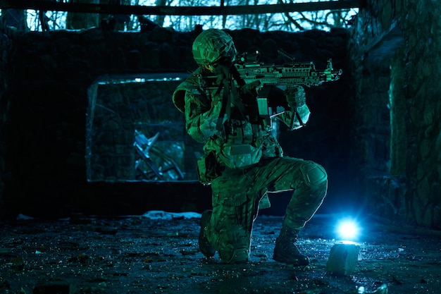 Portrait of airsoft player in professional equipment with machine gun in abandoned ruined building. Soldier with weapons at war