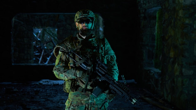 Portrait of airsoft player in professional equipment with\
machine gun in abandoned ruined building. soldier with weapons at\
war