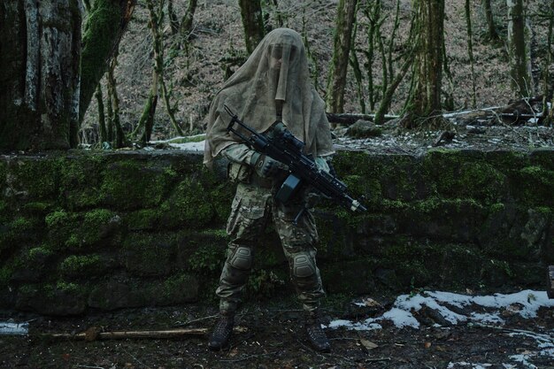Портрет страйкбола в профессиональном оборудовании с пулеметом в лесу. Солдат с оружием на войне