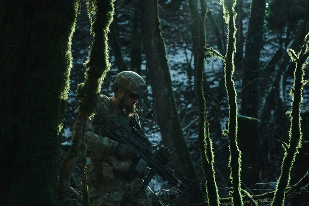 숲에서 기관총을 가진 전문 장비에 있는 airsoft 선수의 초상화. 전쟁에서 무기를 든 군인