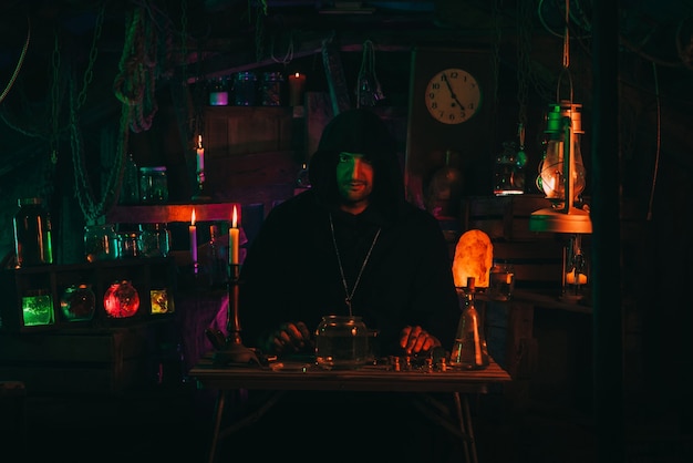 Photo portrait of alchemist magician in interior of dark laboratory workshop with flasks and equipment