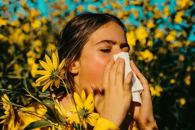 魅力的な明るい黄色のセーターを着て季節の花に囲まれたアレルギーの女性の肖像画